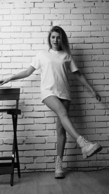 Stüdyoda sandalyenin yanında uzun saçlı, siyah beyaz bir kadın poz veriyor..  