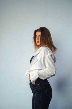 Stüdyoda beyaz bir duvara poz veren uzun saçlı seksi ve şehvetli genç bir kadının fotoğrafı..  