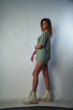 Stüdyoda beyaz bir duvara poz veren uzun saçlı seksi ve şehvetli genç bir kadının fotoğrafı..  