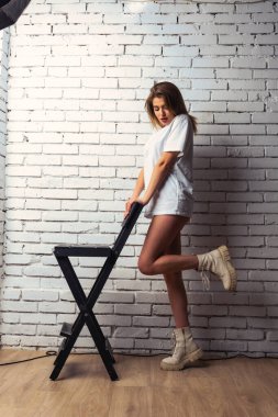 Stüdyoda beyaz bir duvara poz veren uzun saçlı seksi ve şehvetli genç bir kadının fotoğrafı..  