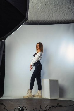 Stüdyoda beyaz bir duvara poz veren uzun saçlı seksi ve şehvetli genç bir kadının fotoğrafı..  