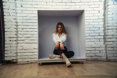 Stüdyoda beyaz gömlekli seksi ve seksi bir kadının beyaz bir duvara poz verdiği bir fotoğraf..  