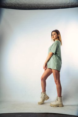 Stüdyoda beyaz bir duvara poz veren uzun saçlı seksi ve şehvetli genç bir kadının fotoğrafı..  
