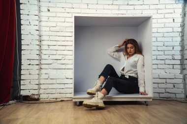 Stüdyoda beyaz gömlekli seksi ve seksi bir kadının beyaz bir duvara poz verdiği bir fotoğraf..  