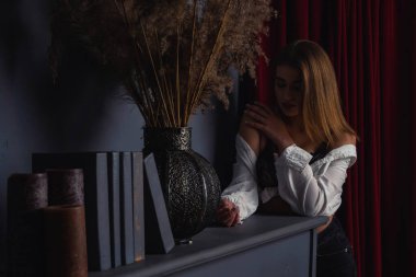 Stüdyoda piyanonun yanında poz veren uzun saçlı, güzel, şehvetli ve seksi bir kadının fotoğrafı..  