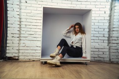 Stüdyoda beyaz gömlekli seksi ve seksi bir kadının beyaz bir duvara poz verdiği bir fotoğraf..  