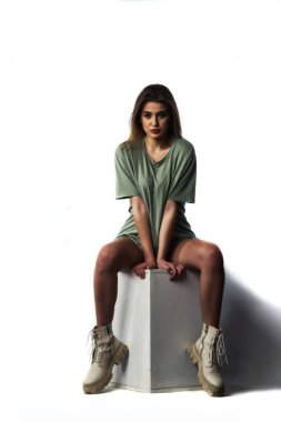 Stüdyoda beyaz bir duvara poz veren uzun saçlı seksi ve şehvetli genç bir kadının fotoğrafı..  