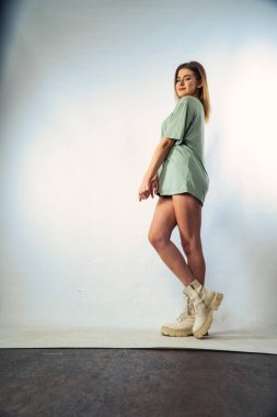 Stüdyoda beyaz bir duvara poz veren uzun saçlı seksi ve şehvetli genç bir kadının fotoğrafı..  