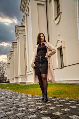 Antik mimarinin yanında kameraya poz veren güzel, genç, zarif bir kadın.