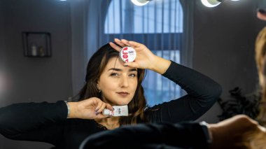 Güzel genç bir kadın aynanın karşısında hazırlanıyor, kişisel bakım konsepti. 