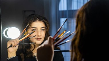 Güzel genç bir kadın aynanın karşısında hazırlanıyor, kişisel bakım konsepti. 