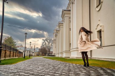 Antik mimarinin yanında kameraya poz veren güzel, genç, zarif bir kadın.