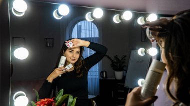 Güzel genç bir kadın aynanın karşısında hazırlanıyor, kişisel bakım konsepti. 