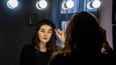 Güzel genç bir kadın aynanın karşısında hazırlanıyor, kişisel bakım konsepti. 