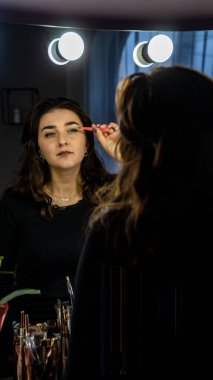 Güzel genç bir kadın aynanın karşısında hazırlanıyor, kişisel bakım konsepti. 