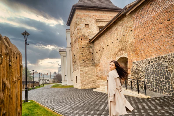 Antik mimarinin yanında kameraya poz veren güzel, genç, zarif bir kadın.