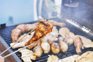 Man cooking meat on barbecue for summer family dinner in the backyard of the house.