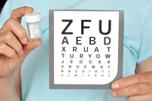 コンタクトレンズケースとスネレンアイチャートを持つ女性 視力検査図を持っている若い医師は コンタクトレンズの正しいビジョンを示しています — ストック写真