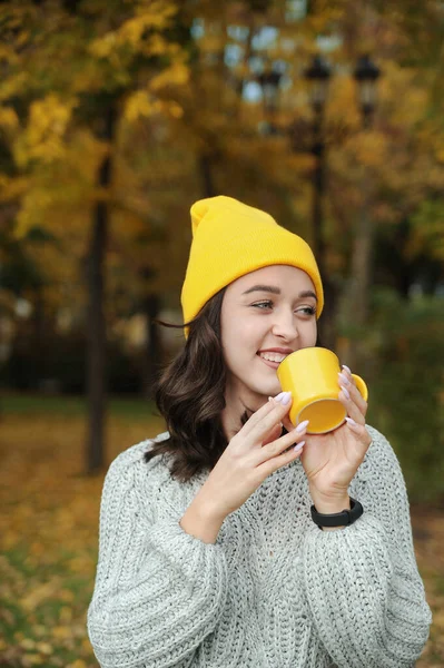 Όμορφη Χαμογελαστή Γυναίκα Κίτρινο Καπέλο Κρατώντας Ένα Φλιτζάνι Στο Πάρκο — Φωτογραφία Αρχείου