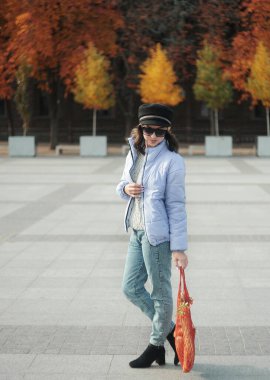  Güneş gözlüklü kadın elinde torba ve kağıt kahve tutuyor.