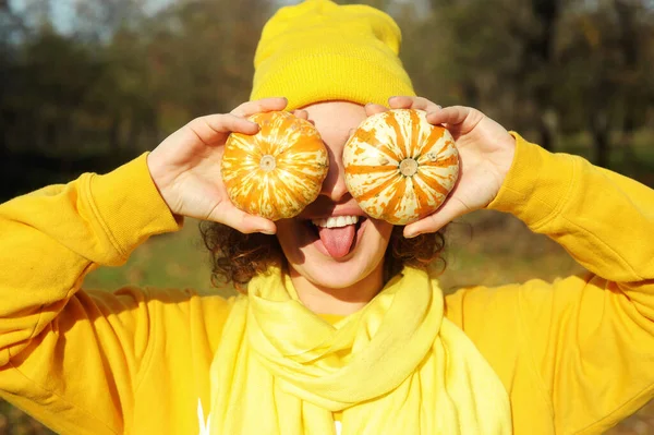 Smiling curly hair woman with pumpkins posing in the autumn park.