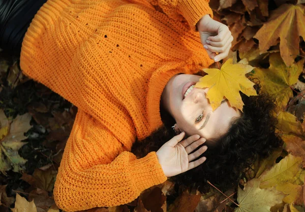 秋天叶子的年轻微笑的女人在秋天的公园里玩得很开心 毛茸茸的快乐女人的画像躺在室外的树叶上 — 图库照片