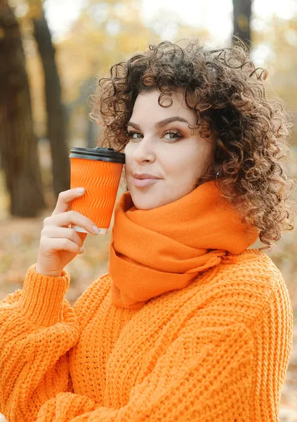 Όμορφη Γυναίκα Πορτοκαλί Πουλόβερ Πλέξιμο Εκμετάλλευση Κύπελλο Καφέ Στο Πάρκο — Φωτογραφία Αρχείου