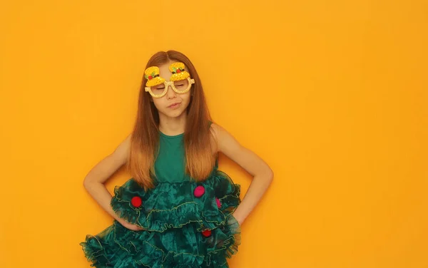 Criança Bonito Vestido Festivo Verde Óculos Natal Posando Fundo Amarelo — Fotografia de Stock