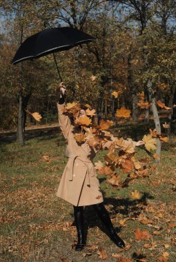 Sonbahar yapraklı kadın sonbahar parkında eğleniyor. Dışarıdaki yeşillikte kıvırcık saçlı mutlu bir kadının portresi.. 