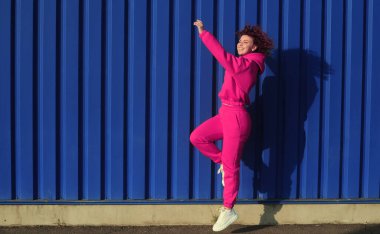 Gülümseyen mutlu kadın konsepti. Arka planda güzel kıvırcık saçlı kadın. Açık havada poz veren mor kapüşonlu kıvırcık saçlı pozitif kadın..