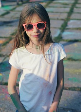 Küçük kız Holi festivalinde boyalarla eğleniyor.