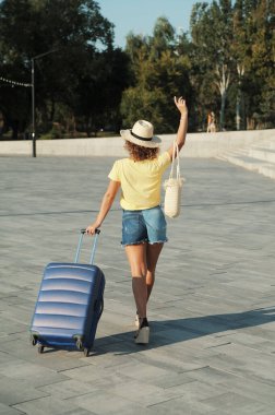 Şapkalı, bavullu, tatilde güzel bir kadın.