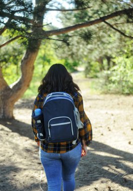 Sırt çantalı genç bir kadın yürüyüşe çıkıyor.