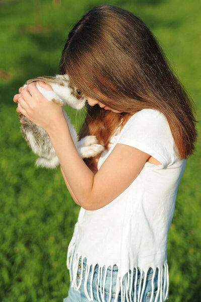 The child hugs a little rabbit. Easter symbol. Friendship between child and animal.
