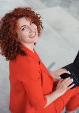  Business woman in red clothes works with laptop ooutdoors.