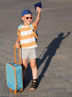little boy with suitcase on the road