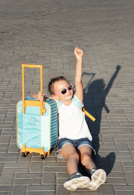 Bavullu küçük kız dışarıda otobüs bekliyor.