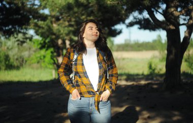 Sırt çantalı genç bir kadın yürüyüşe çıkıyor. Ormanda ekose gömlekli güzel bir kadın.