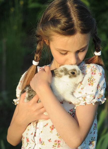 Kid with little rabbit on grass.