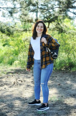 Sırt çantalı genç bir kadın yürüyüşe çıkıyor. Ormanda ekose gömlekli güzel bir kadın.