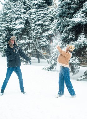 Karla oynayan kadın ve erkek. Mutlu çift dışarıda eğleniyor..
