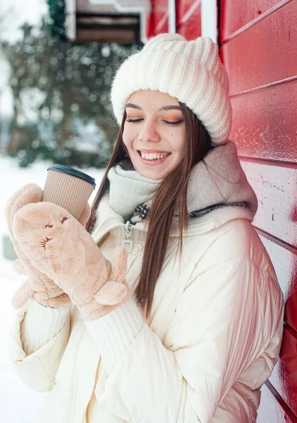밖에서 마시는 뜨거운 음료를 마시는 여자는 눈내리는 날씨에 공원에서 재미를 — 스톡 사진