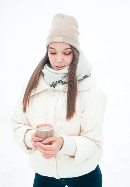 屋外でお茶を飲む女性の肖像画 雪の日の公園では 熱い飲み物のカップを持つ若い女性が楽しいです — ストック写真