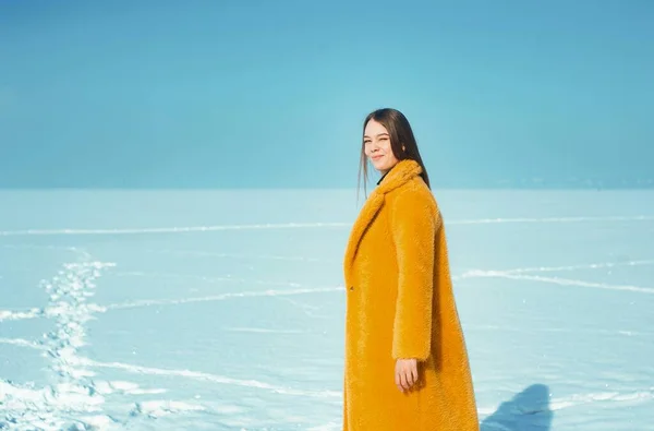 穿着黄色外套的年轻漂亮的女人在雪地的冰上行走 — 图库照片