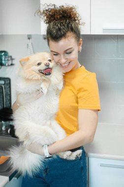 Kıvırcık saçlı kadın evde köpeğiyle oynuyor..