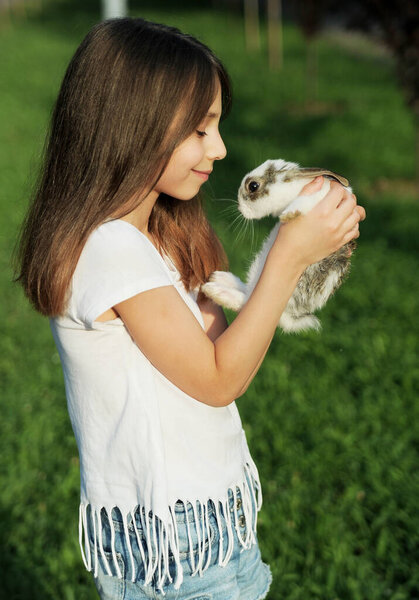 Girl hugging baby rabbit outdoors
