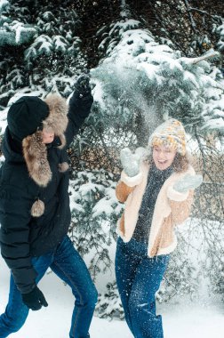 Kadın ve erkek kış ormanlarında yürüyorlar. Mutlu çift karla eğleniyor.. 