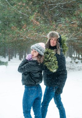 Mutlu çift karla eğleniyor. Kadın ve erkek kış ormanlarında yürüyor. 