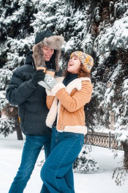 Mutlu çift karla eğleniyor. Kadın ve erkek kış ormanlarında yürüyor. 