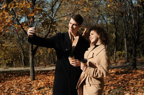 Young man in dark coat and woman in trendy beige coat